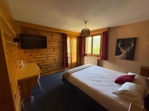a bedroom with a bed and a desk and a television at Hôtel Restaurant La Pendine in Puy-Saint-Vincent