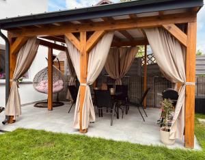 a pavilion with curtains and a table and chairs at Pokoje Gościnne REST in Karwia