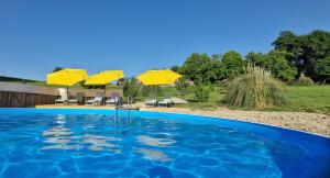 a swimming pool with yellow umbrellas and chairs at Gauguin in Douzains