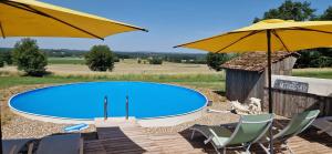 a swimming pool with chairs and an umbrella at Monet in Douzains