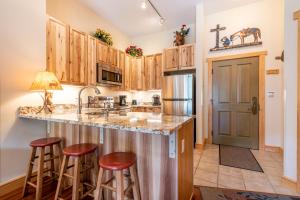 a kitchen with wooden cabinets and a large island with bar stools at Copper Springs Lodge 433 in Copper Mountain +32 photos