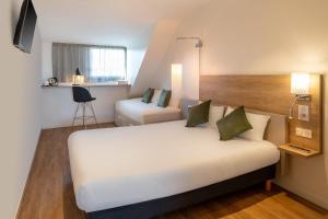 a hotel room with a large white bed and a chair at Sure Hotel by Best Western Dijon Sud in Chenôve +52 photos