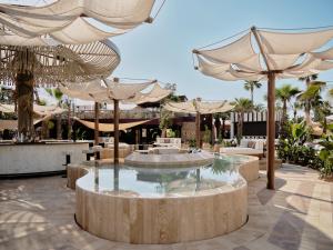 a patio with a fountain with umbrellas and tables at BLESS Ibiza The Site - New Opening 2026 in Playa d'en Bossa +95 photos