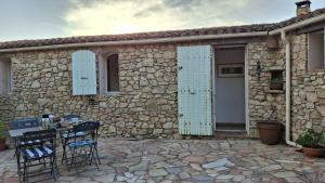 a stone building with blue shutters and a table and chairs at Maison Cistaredda in Sotta