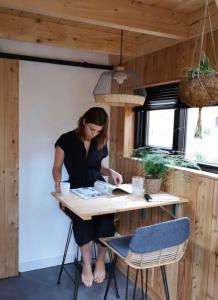 a woman sitting at a table reading a book at Tiny House of Happiness - shared hot tub in Otterlo +23 photos