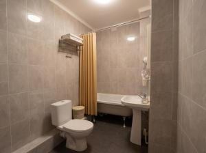 a bathroom with a toilet and a sink and a tub at Oasis Hostel in Kostanay