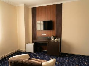 a hotel room with a couch and a television at Oasis Hostel in Kostanay +6 photos