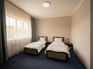 two beds in a room with a window at Oasis Hostel in Kostanay