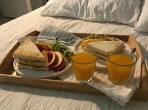 a tray of sandwiches and fruit and two glasses of orange juice at Oasis Hostel in Kostanay