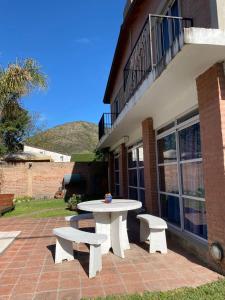 a picnic table and two benches on a brick patio at Casa de vacaciones Naty in Villa Carlos Paz
