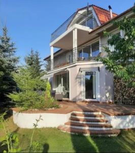 a large white house with stairs in front of it at Willa Myśliwska Giżycko in Giżycko