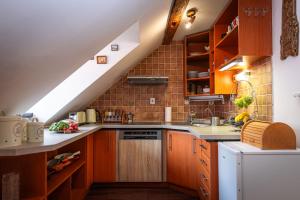 an attic kitchen with wooden cabinets and a sink at Libling Podkrovný in Banská Štiavnica +19 photos