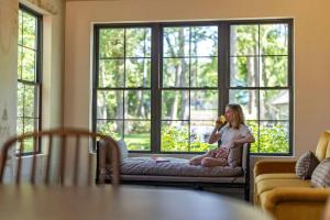 a girl sitting on a couch in front of a window at Maison Foxglove - Petite Acres Chateau in New Buffalo