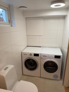 a bathroom with a washing machine and a toilet at Lägenhet 36B in Båstad