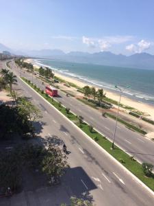 a road next to a beach with a red bus at Gia Huy Guesthouse in Da Nang