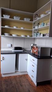 a kitchen with white counters and shelves with dishes at Hostel Villa Nova in Mossel Bay +12 photos