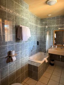 a bathroom with a tub and a sink at Hôtel Restaurant La Pendine in Puy-Saint-Vincent +40 photos