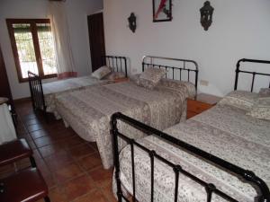 1 dormitorio con 3 camas y ventana en Alojamientos rurales La Torca, en Fuente de Piedra