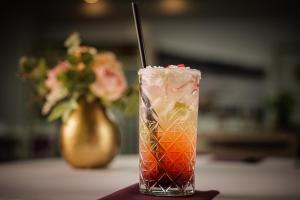 a drink sitting on a table with a vase of flowers at Penzión Aqua Maria in Veľaty
