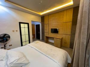a bedroom with a white bed and a tv on a wall at MOTISOFT Hotel in Yenagoa