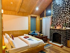 a bedroom with a bed and a fireplace at Tirthan Wood , a river view cottage in Banjār