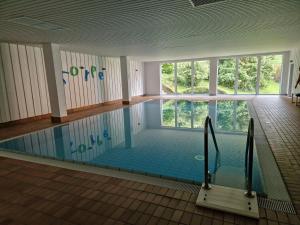 a swimming pool in a building with a large window at Traumwohnung am Sorpesee in Sundern