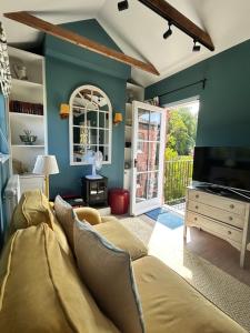 a living room with a couch and a tv at Cockloft Romantic Countryside Hideaway in Bishops Cannings