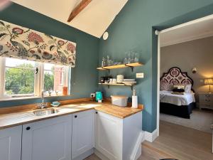 a kitchen with a sink and a window with a bed at Cockloft Romantic Countryside Hideaway in Bishops Cannings