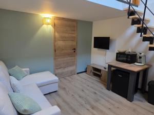 a living room with a white couch and a tv at L oasis de Détente - le Cocon - gîte 4 personnes avec 1h d accès à la piscine privée et terrasse aménagée par nuit réservée - climatisation - à 2km de Pairi Daiza in Brugelette