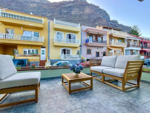 a patio with two chairs and a table and some buildings at La Casa de Papel 2 in Valle Gran Rey +3 photos