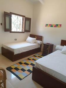 a bedroom with two beds and a window and a rug at Nobal best house in Aswan