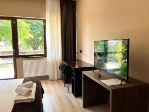 a hotel room with a desk and a large screen television at Villa Petra Residence - Private Parking & Village Life in Cristian