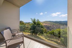 a balcony with a chair and a large window with a view at Agua Hotels Mondim de Basto in Mondim de Basto