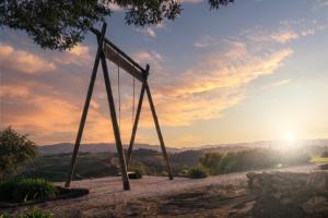 a swing on a hill with the sunset in the background at Agua Hotels Mondim de Basto in Mondim de Basto