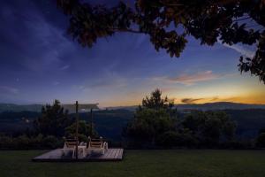 two chairs and an umbrella in a field with the sunset at Agua Hotels Mondim de Basto in Mondim de Basto