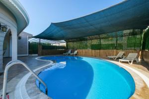 a swimming pool in a backyard with a patio with chairs at Villa ay yıldız in Belek