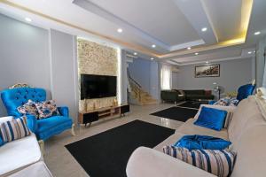 a living room with blue chairs and a large tv at Villa ay yıldız in Belek