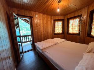 a bed in a wooden room with a window at Vikendica Jablaničko jezero in Jablanica