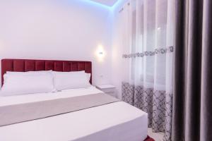 a bedroom with a white bed and a window at Sunrise Hotel Vila in Vlorë