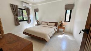 a bedroom with a bed and two windows at Maprao Tropical Home in Ko Phangan