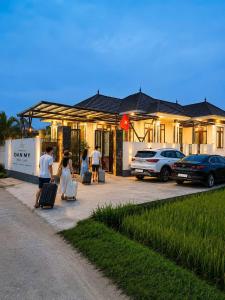 a group of people standing outside of a house with luggage at Homestay ĐAN MY 2 in Trung Nghĩa