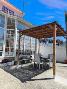 a patio with a table and chairs under a wooden pergola at Chalet cerca de la playa de Esmelle in Pedreira