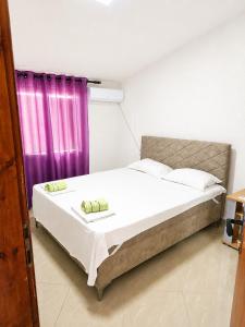a bedroom with a bed with a purple curtain at Esko Rooms in Donji Štoj