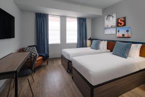 a hotel room with two beds and a desk at Hotel Rendale Miami Beach in Miami Beach