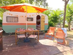 an rv with a table and chairs under an umbrella at Camping Arribes del Duero in Lumbrales +19 photos