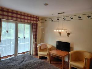 a bedroom with a bed and a television and chairs at Apartment 35, 36 Christopherhof Grafenwiesen in Grafenwiesen