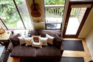 a living room with a couch with pillows and a guitar at Rivers Edge at Snowater in Glacier