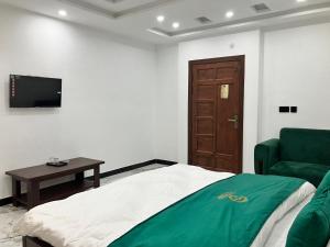 a bedroom with a bed and a chair and a television at Landmark Hotel & Resort in Taiwāl