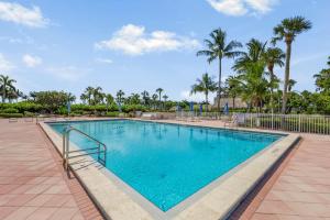 a swimming pool at a resort with palm trees at SW facing beachfront condo with sweeping ocean views in Marco Island