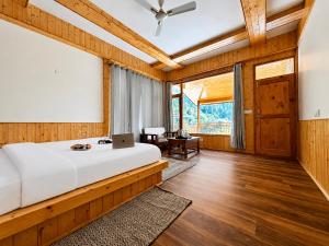 a bedroom with a bed with a laptop on it at Tirthan Wood , a river view cottage in Banjār
